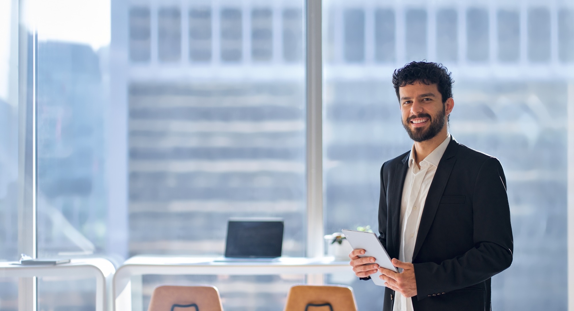 Corporate manager office worker looking at camera holding digital tablet